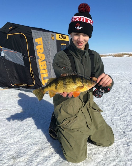The author’s son, Elliott, steps out of the ice shelter to show off the duo’s first camera fish.