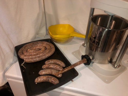 Use a mechanical sausage stuffer to fill natural hog casings with the meat mixture.