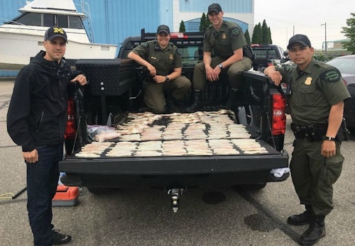 Left to right: Michigan Conservation Officers David Schaumburger, Danielle Zubek, Adam Beuthin and Keven Luther show walleye fillets and carcasses confiscated from two brothers who were poaching on the Detroit River in May 2018. Image courtesy of Michigan DNR.