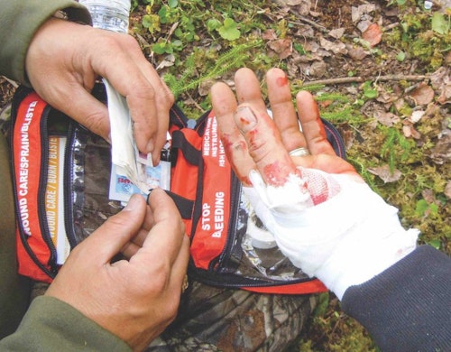 The author helps bandage the hand of an outfitter who cut himself during a skinning job in the backcountry.